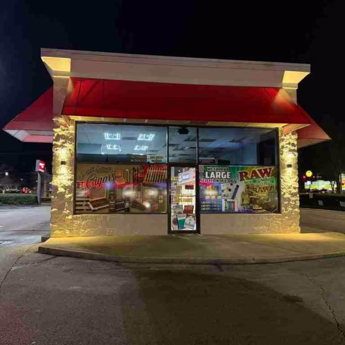 Side view of Cigarette City Store by JD Stores displaying banners with cigar images and text: "We carry a large selection of cigarettes."